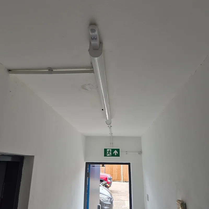 LED batten and emergency exit sign fitted above a doorway