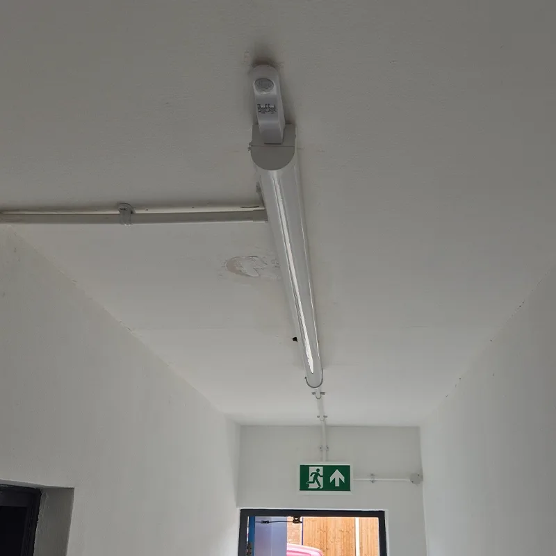 LED batten with PIR sensor and emergency exit sign fitted to a ceiling
